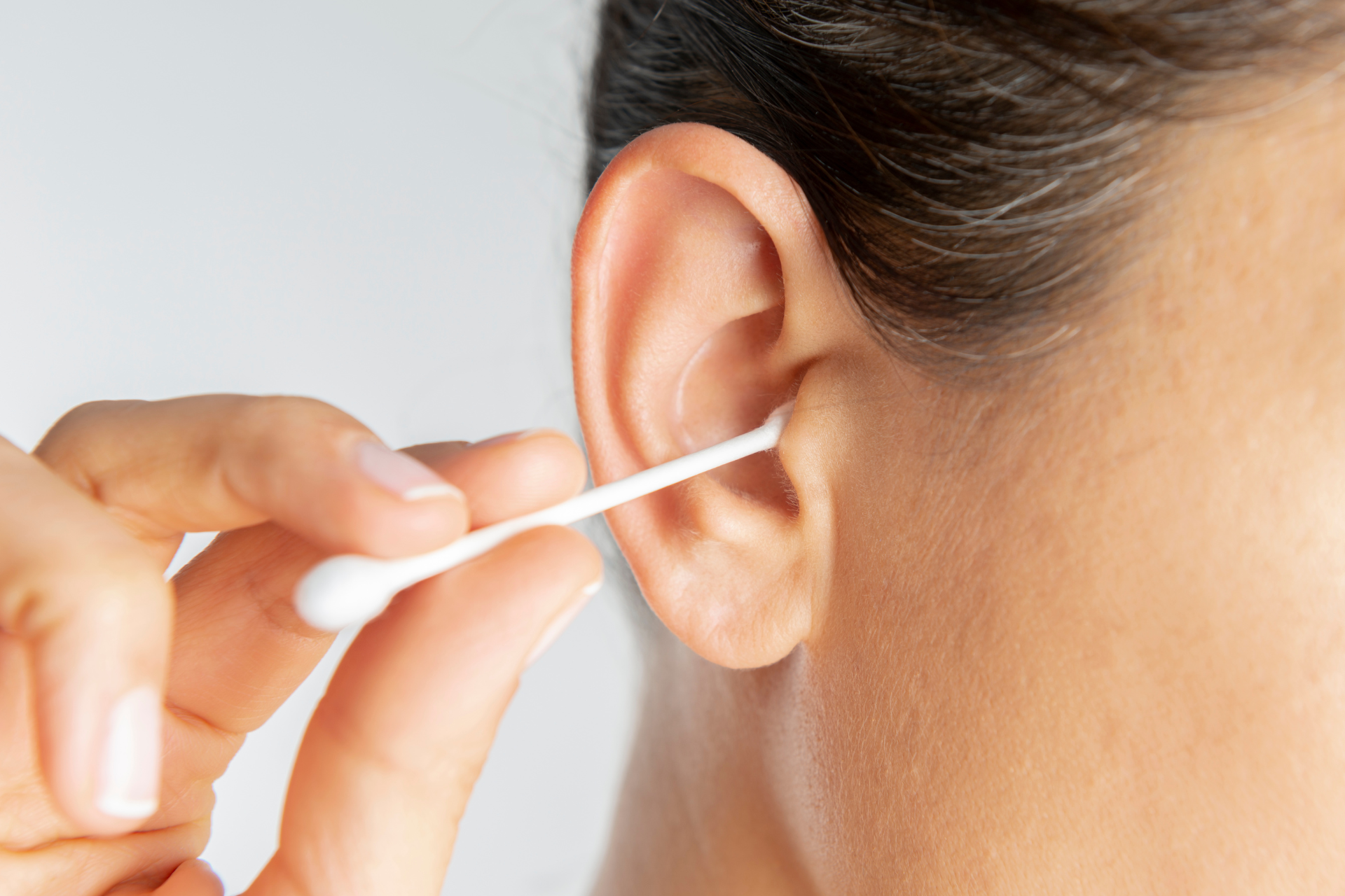 Foreign objects stuck in the ear canal Person putting a cotton swab in her ear