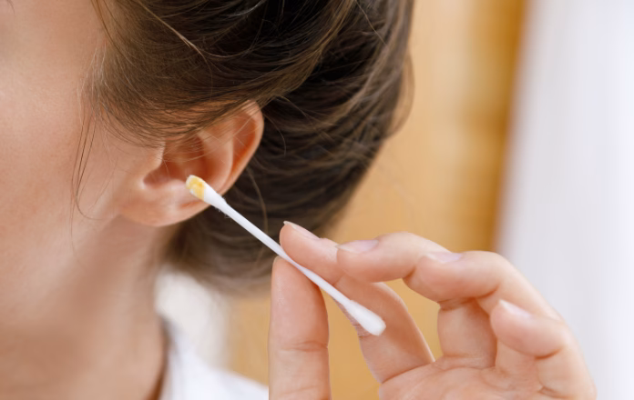 Woman sticking cotton swab inside ear