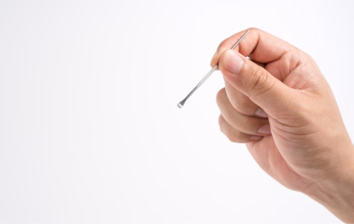 Person holding a metal ear digger tool